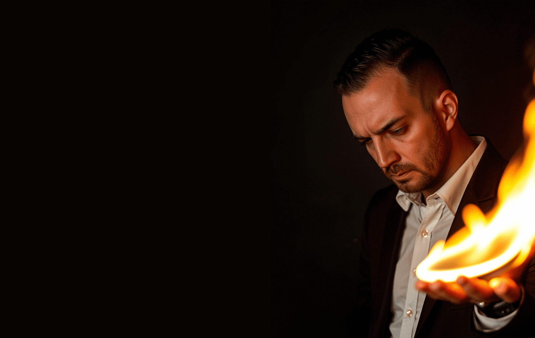 Chris Dare gazing at a flame rising from his open hand