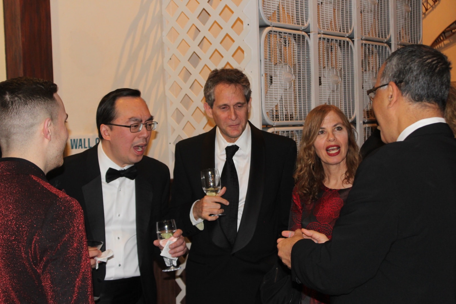 Guests in formalwear shouting in amazement during a card trick at a black-tie event