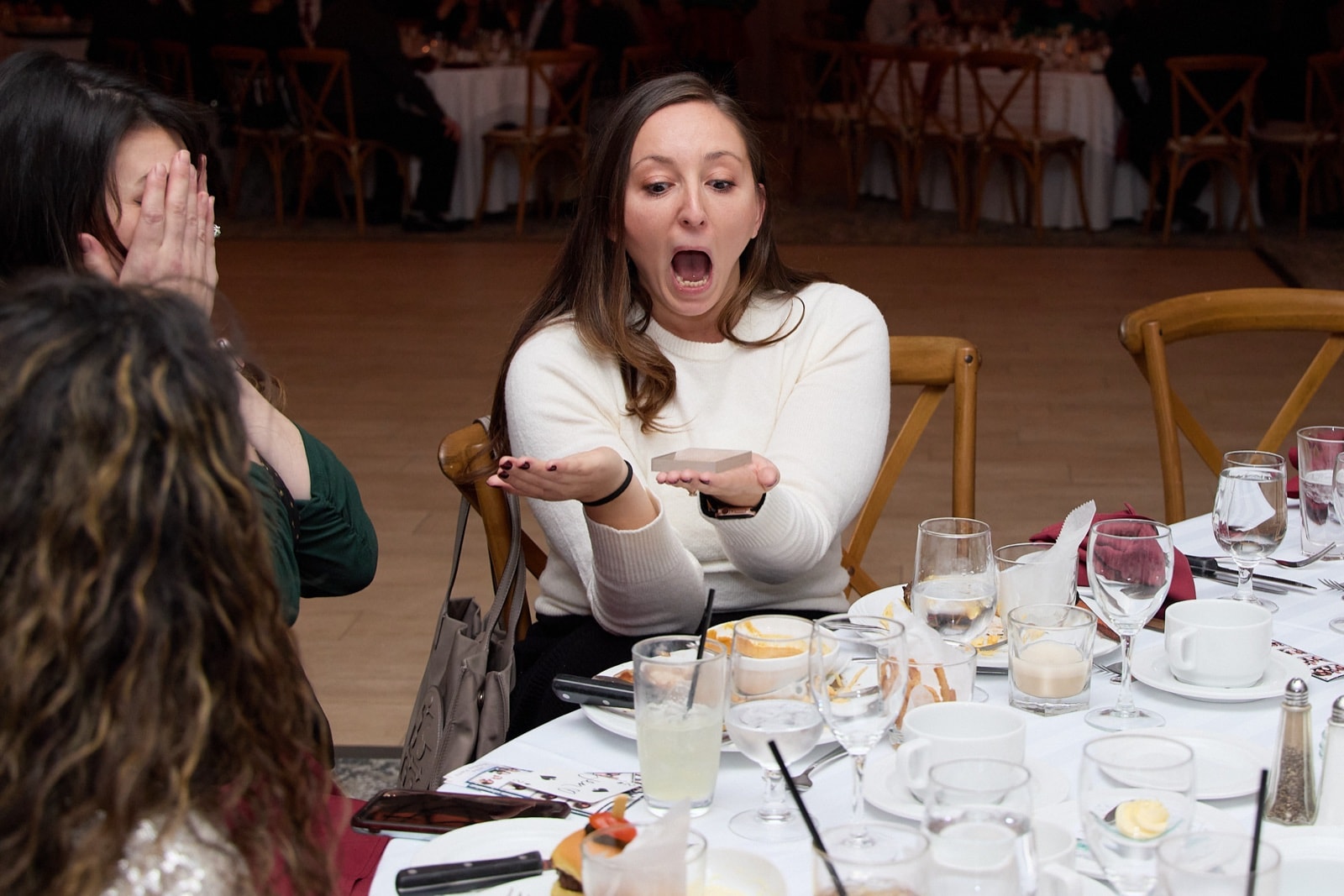 A dinner guest gasping with her hands out after a reveal by Chris Dare