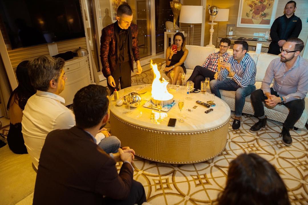 Guests watching a candle-lit table illusion during a private suite show