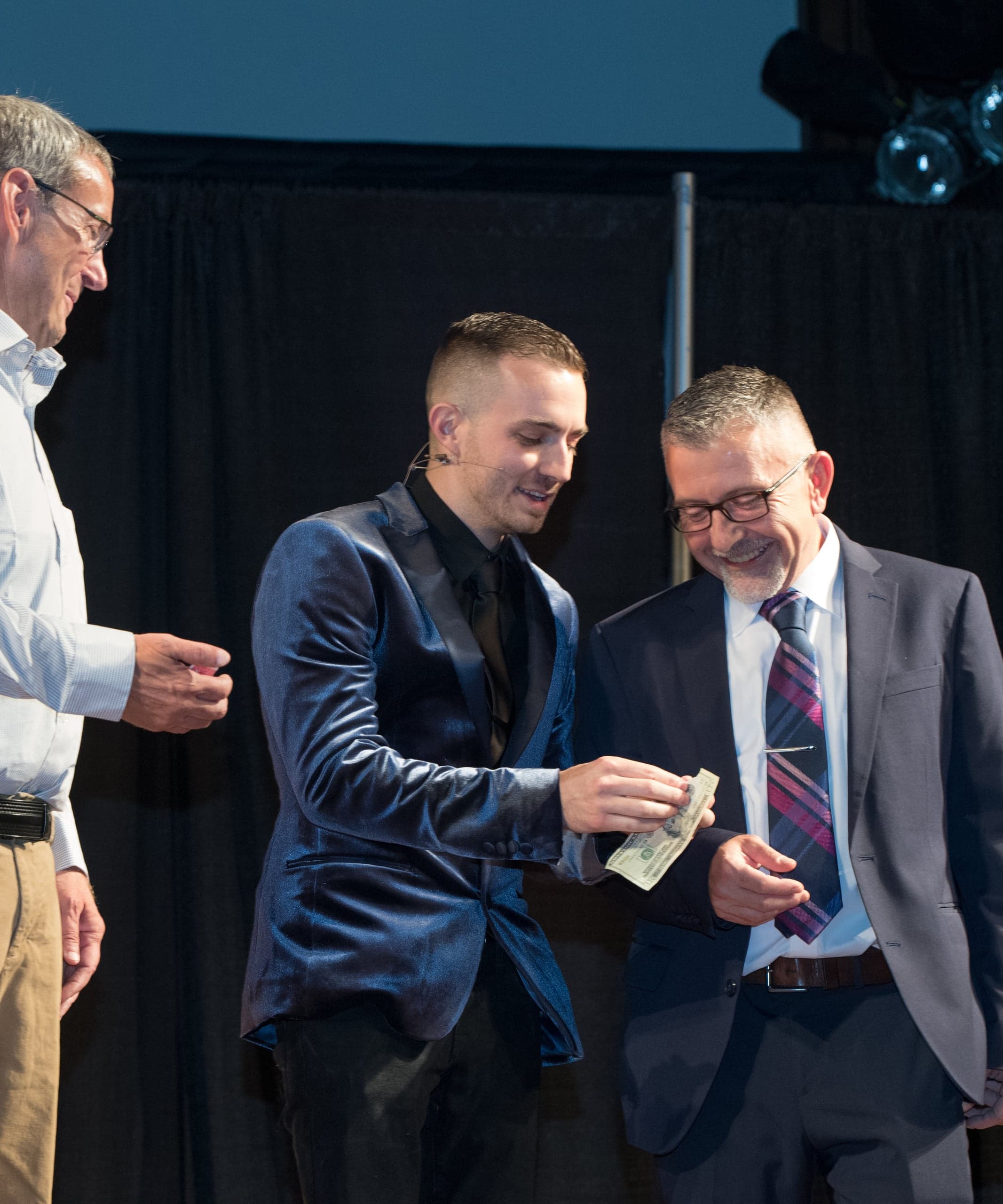 Chris Dare returns a borrowed hundred dollar bill to a laughing volunteer during a corporate stage show