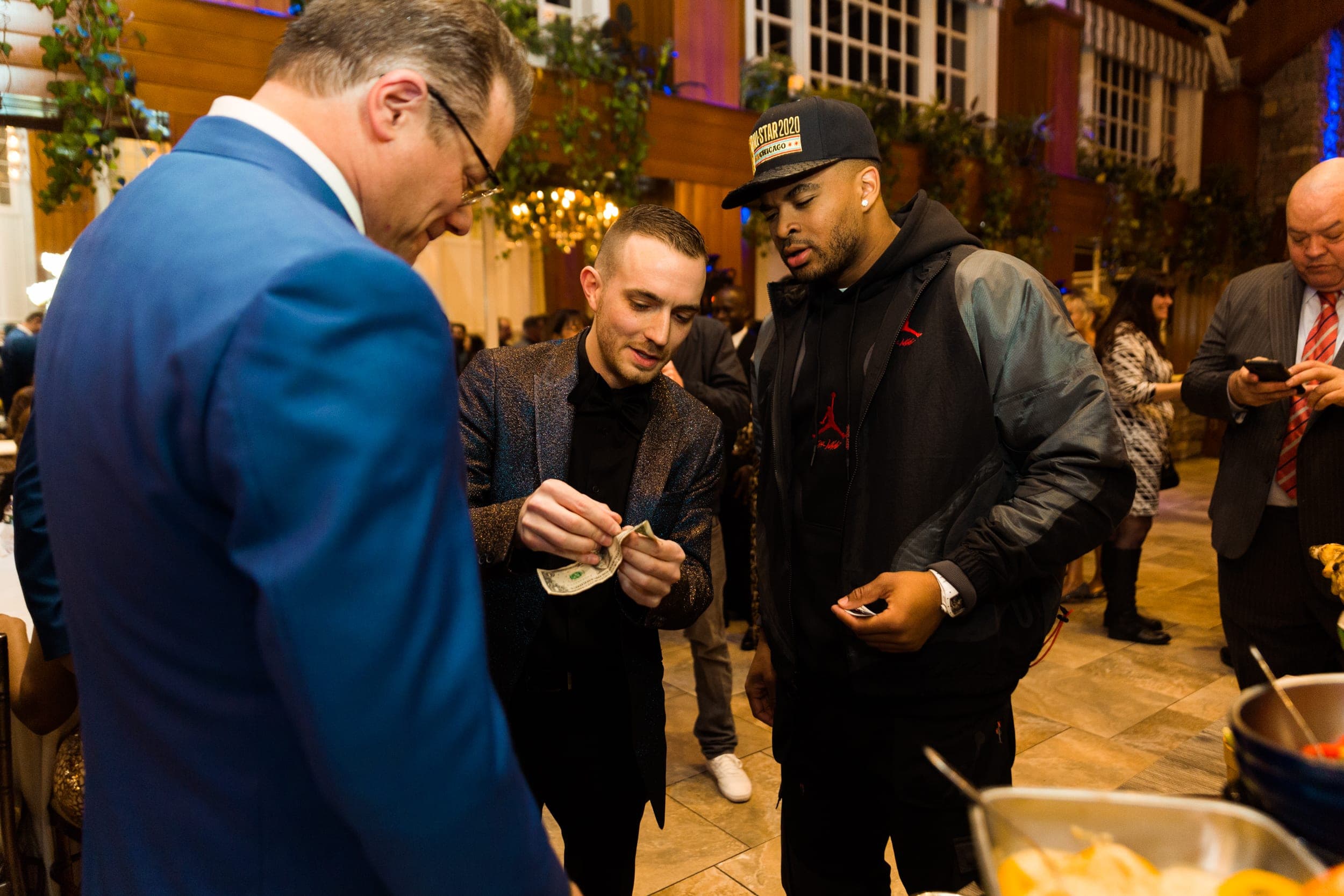 Chris Dare folds a borrowed bill for amazed onlookers at a VIP reception